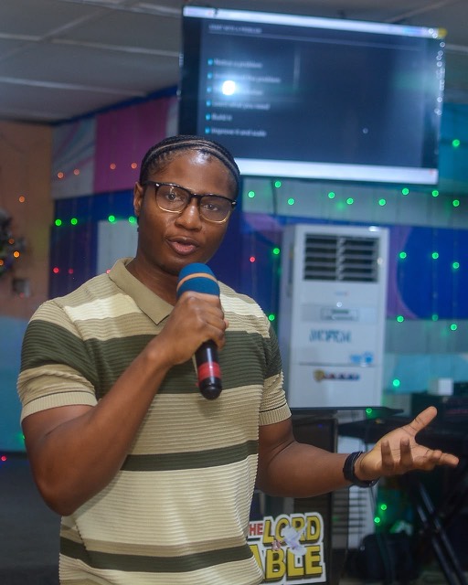 Somkene speaking on stage in front of a slide titled Start with a problem